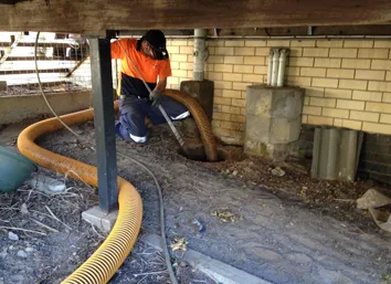 Worker installing seepage control system under house